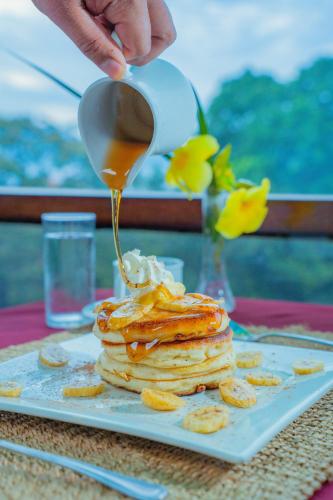 a person is pouring syrup onto a stack of pancakes at Puerto Pension Inn in Puerto Princesa City