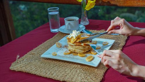a person cutting a plate of pancakes on a table at Puerto Pension Inn in Puerto Princesa City