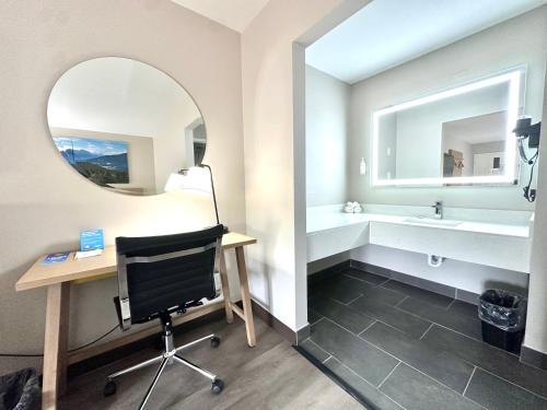 a bathroom with a desk and a mirror at Days Inn & Suites by Wyndham Bossier City - Casino Area in Bossier City