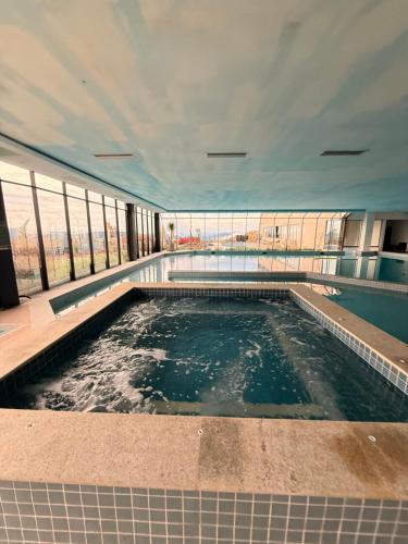 a swimming pool in a building with windows at Resort Gran Paradiso - apartamento com vista in Campos do Jordão