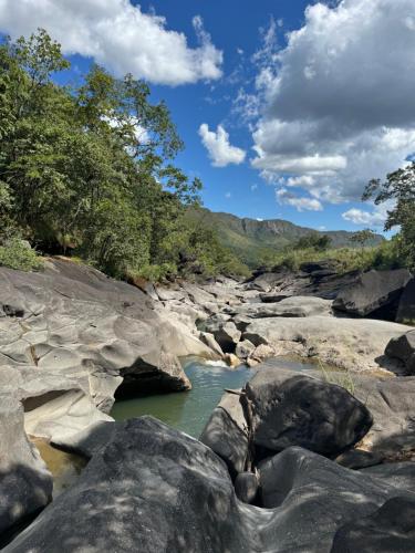 a river in the middle of rocks and trees at Castelo de pedras no Vale da Lua in Alto Paraíso de Goiás