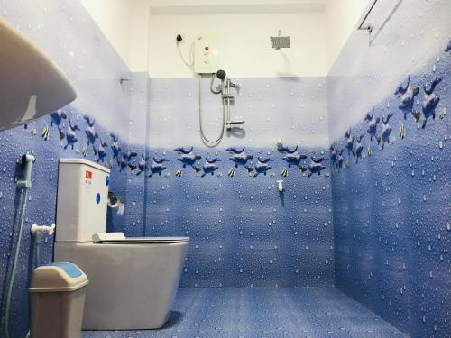 a blue bathroom with a toilet and a shower at Darshani Lodge in Sigiriya