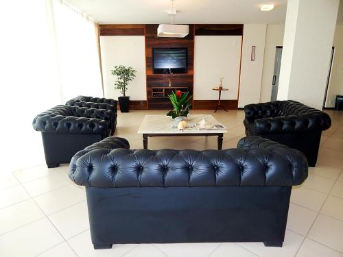 a living room with two black leather couches and a table at Rede Andrade Atlântico in Piçarras