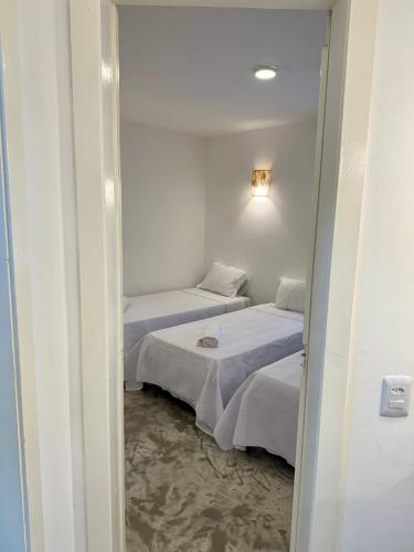 two beds in a small room with a doorway at Pousada Gipoia in Angra dos Reis