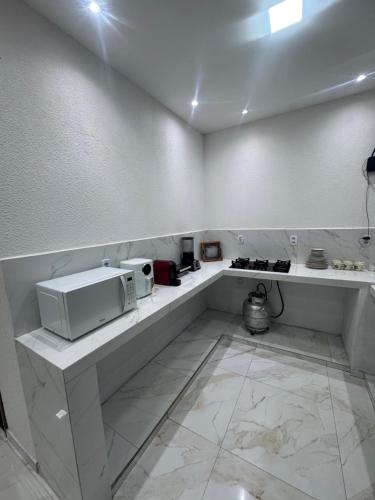 a white kitchen with a microwave on a counter at Lençóis House in Barreirinhas