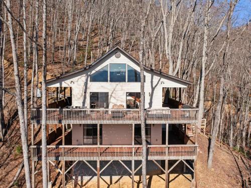 a house with a large deck in the woods at Lazy Bear Retreat Mountain Views-Hot Tub-FirePit in Whittier