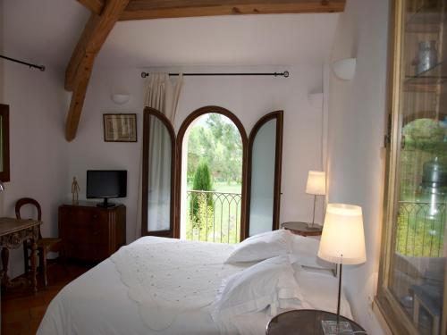 a bedroom with a bed and a large window at La Ferme Rose-Hôtel de Charme in Moustiers-Sainte-Marie