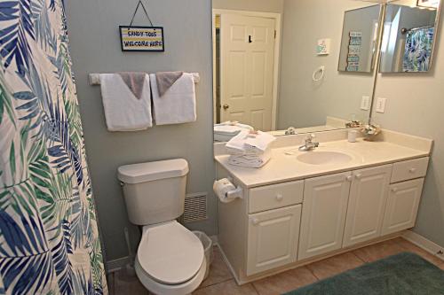 a bathroom with a toilet and a sink and a mirror at Cypress Point in Gulf Shores
