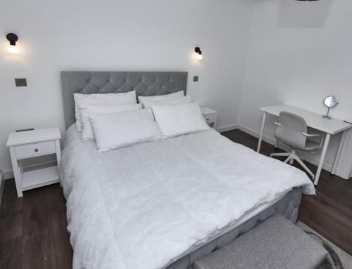 a bedroom with a large white bed and a desk at Apartment in Buckinghamshire with Secured Parking in Buckinghamshire