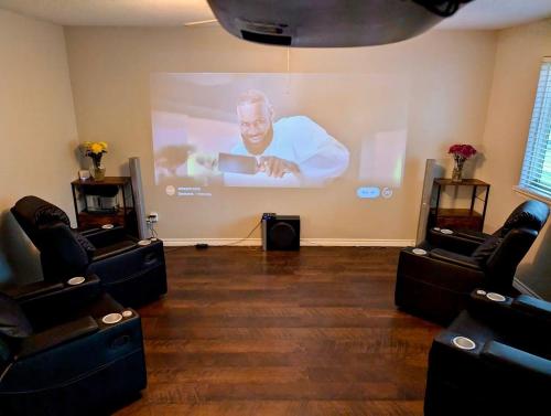 a room with a large screen with a man on a projector at By Popular Demand - Houston in Houston