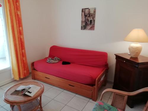 a small red bed in a room with a table at Charming Chalet with Swimming Pool in Quend in Quend