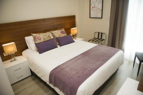 sypialnia z dużym łóżkiem z fioletowymi poduszkami w obiekcie Manolia City Residences w Nikozji