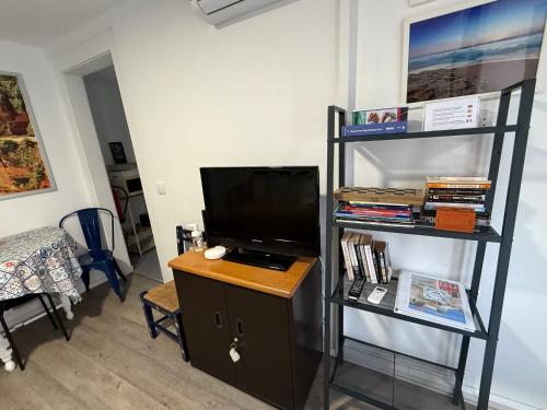 a living room with a tv and a book shelf at Apartamento com pátio em frente praia in Paço de Arcos