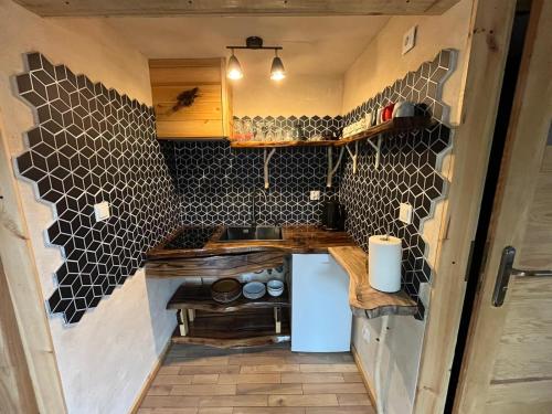 a small kitchen with black tiles on the wall at Wąkop 6 Agroturystyka Eco in Nowa Słupia