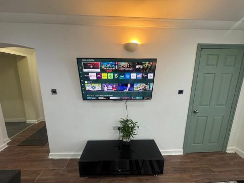 a flat screen tv hanging on a wall with a table at A cozy and spacious apartment in Dudley