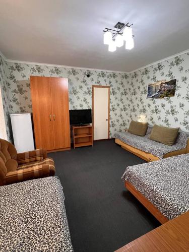 a room with two beds and a television in it at Podsolnukhi Guest House in Cholpon-Ata