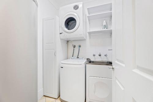 Un baño blanco con lavabo y lavadora. en Margs at Denhams, en Denhams Beach