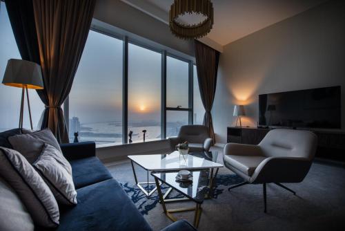 a living room with a blue couch and a large window at Maison Privee - Chic Coastal Escape with Open Sea Vws on Palm Entry in Dubai