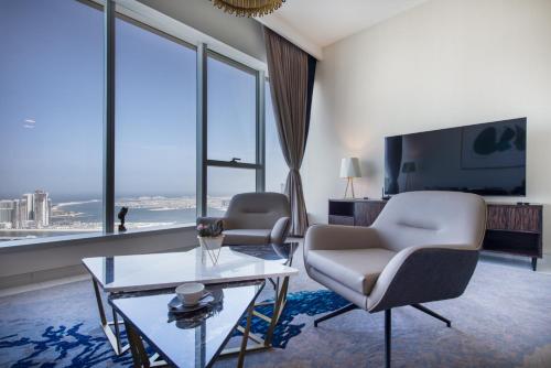 a living room with a couch and chairs and a tv at Maison Privee - Chic Coastal Escape with Open Sea Vws on Palm Entry in Dubai