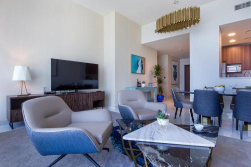 a living room with chairs and a flat screen tv at Maison Privee - Chic Coastal Escape with Open Sea Vws on Palm Entry in Dubai