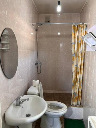 a bathroom with a sink and a toilet and a mirror at Podsolnukhi Guest House in Cholpon-Ata