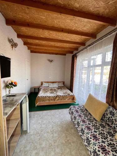 a bedroom with a bed and a couch in a room at Podsolnukhi Guest House in Cholpon-Ata