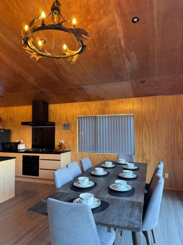 a dining room with a table and chairs and a chandelier at Brand New 4BR Alpine Home Near Turoa Ski Field in Ohakune