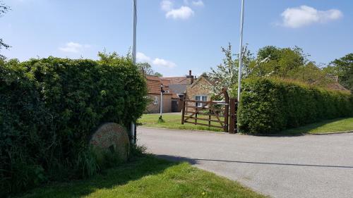 a street with a hedge and a house with a gate at Watermill Farm Cottages in Metheringham