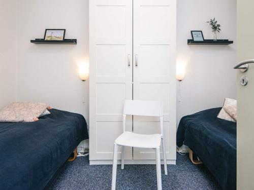 a bedroom with two beds and a white chair at 4 person holiday home in Ringkøbing in Ringkøbing