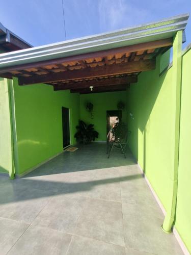 a patio with a green wall and a wooden ceiling at Casa Verde in Holambra