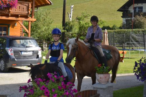 a woman and a child riding on horses at Biobauernhof Tonimörtl in Mariapfarr