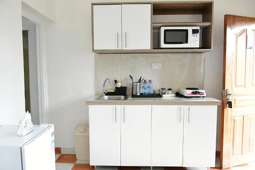 a kitchen with white cabinets and a microwave at Lion Hill Place in Nakuru