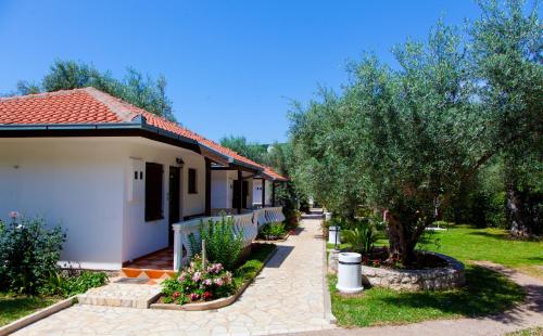 a white house with a tree and a sidewalk at President Bungalows and Apartments in Utjeha