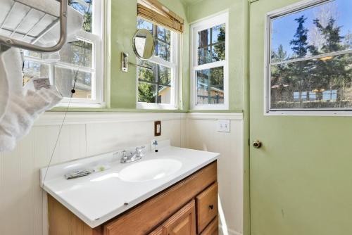 een badkamer met een wastafel, een spiegel en ramen bij FRANK'S OLD BEAR #149 in Big Bear Lake
