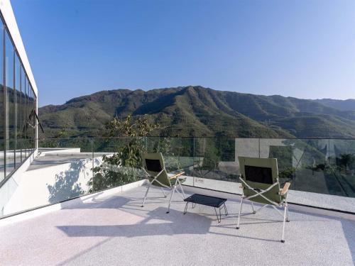 two chairs and a desk on a balcony with a mountain at Jianglu Yalugu Hotel in Kaixuan