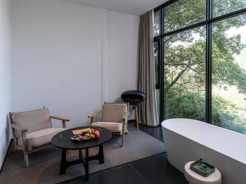 a bathroom with a tub and a table and chairs at Jianglu Yalugu Hotel in Kaixuan