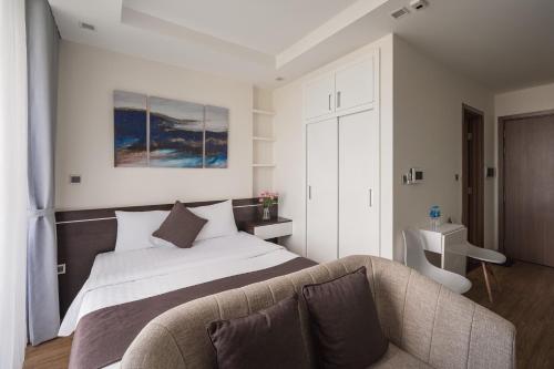 a bedroom with a large bed and a couch at Luxury Studio With Swimming Pool, Gym And Tennis Courts In City Center in Hanoi