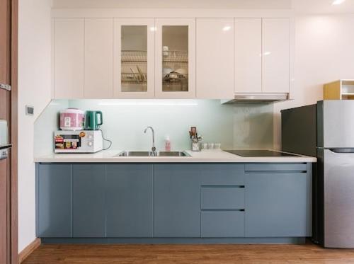 a kitchen with blue and white cabinets and a refrigerator at Luxury Studio With Swimming Pool, Gym And Tennis Courts In City Center in Hanoi