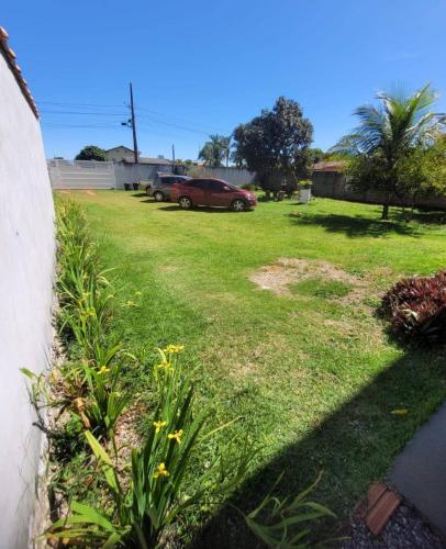 a yard with a green lawn with a red car parked at Flat Morada da Neblina! in Chapada dos Guimarães