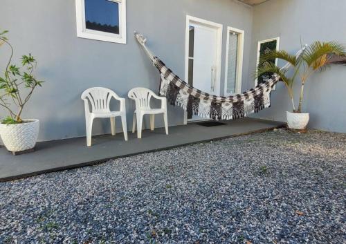 two chairs and a hammock in a house at Flat Morada da Neblina! in Chapada dos Guimarães