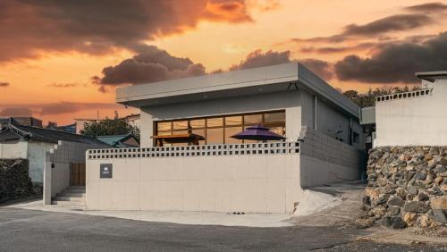 SaegiにあるPohang Noblerest Pensionの夕日を背景にした白い建物