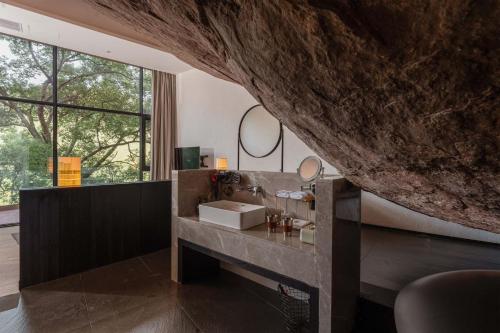 a bathroom with a sink and a large rock at Jianglu Yalugu Hotel in Kaixuan
