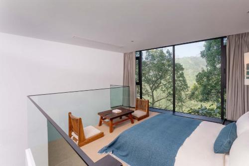 a bedroom with a bed and a desk and a large window at Jianglu Yalugu Hotel in Kaixuan