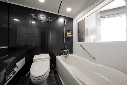 a black and white bathroom with a toilet and a tub at Tokyu Stay Kamata - Tokyo Haneda in Tokyo