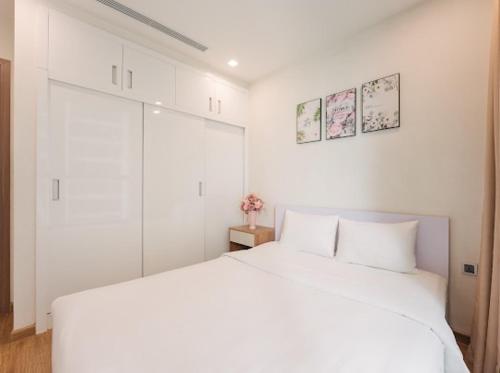 a white bedroom with a large white bed in it at Delux Studio In City Center With Gym, Swimming Pools And A Private Walking Lake in Hanoi