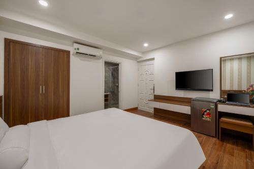 a white bedroom with a bed and a television at Rest Hotel & Apartment in Da Nang