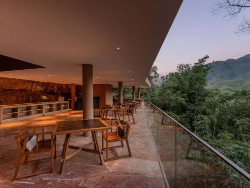 a restaurant with tables and chairs on a balcony at Jianglu Yalugu Hotel in Kaixuan