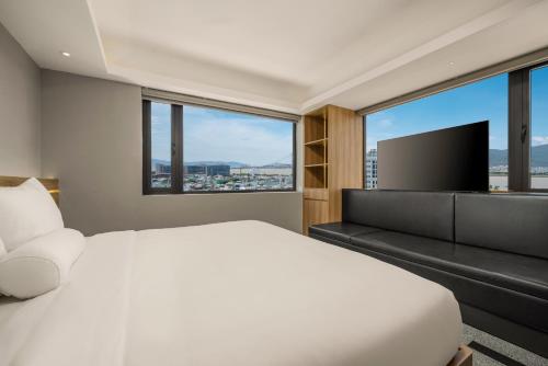 a bedroom with a white bed and a flat screen tv at Rest Hotel & Apartment in Da Nang