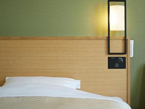 a bedroom with a white bed and a mirror at Candeo Hotels Matsuyama Okaido in Matsuyama