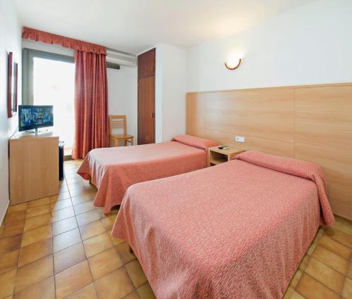 Cette chambre comprend deux lits et une télévision. dans l'établissement Hostal Montaña, à Sant Antoni de Portmany
